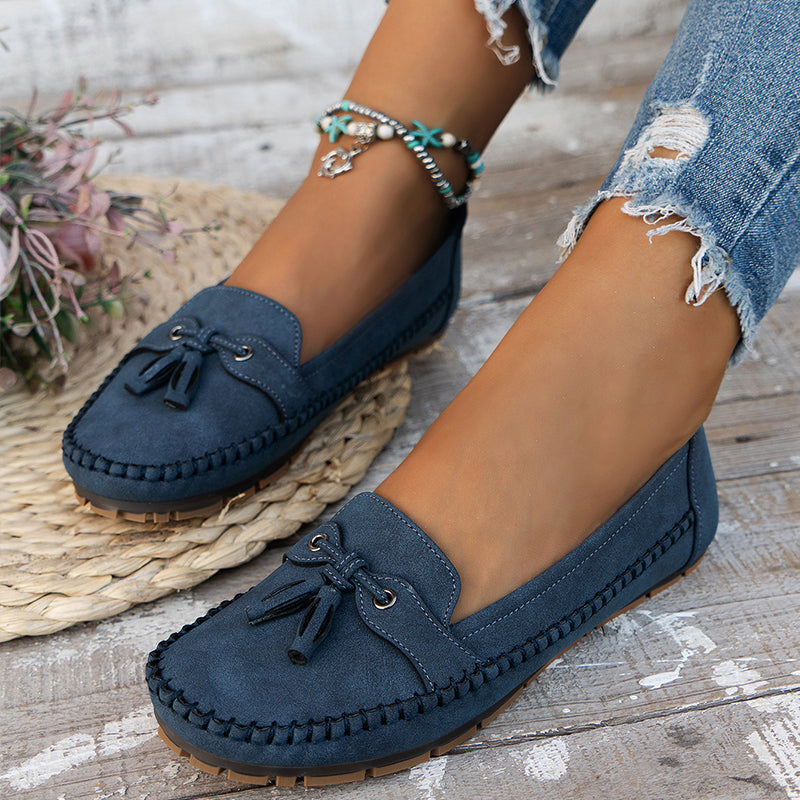 Women's navy loafer with tassel detail, moccasin sole, worn with ripped jeans