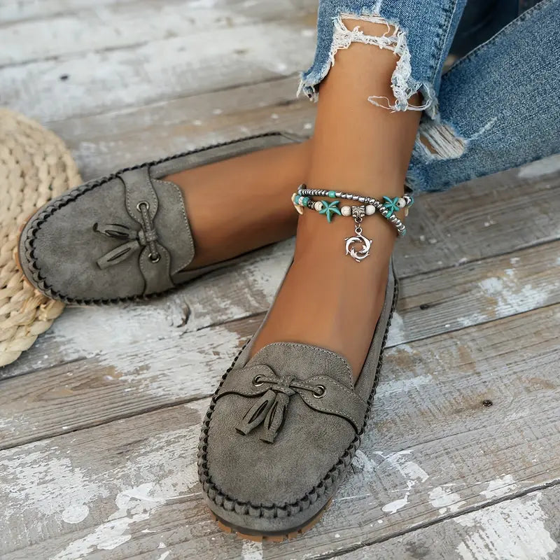 Women's navy loafer with tassel detail, moccasin sole, worn with ripped jeans