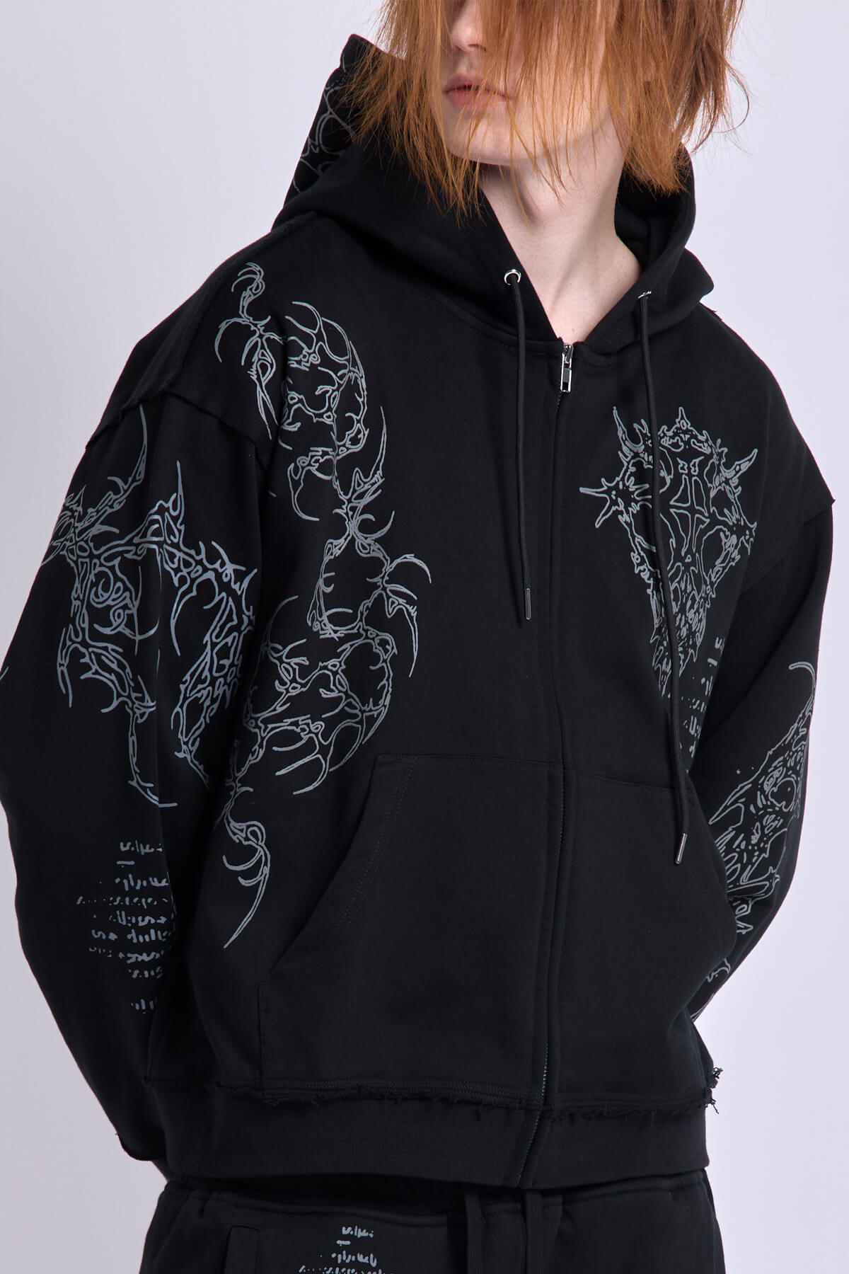 Black unisex zip hoodie with hood, long sleeves and contrasting graphic prints