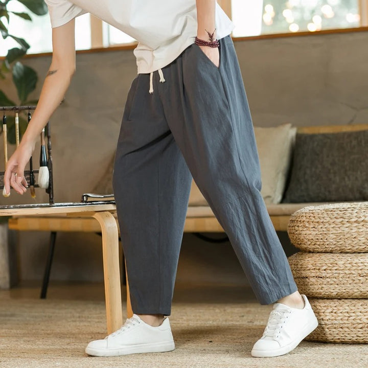 Men's tapered ankle pants with drawstring waist in cream, displayed with white sneakers