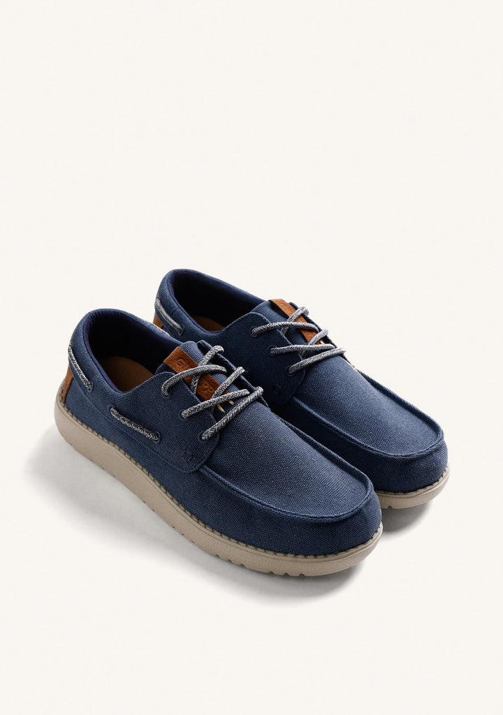 Navy Wallabee loafers with grey laces, brown heel detail and flat textured soles
