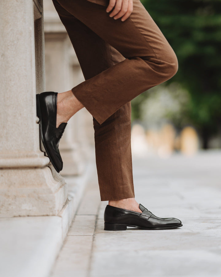 Black polished penny loafers with almond toes and low heels