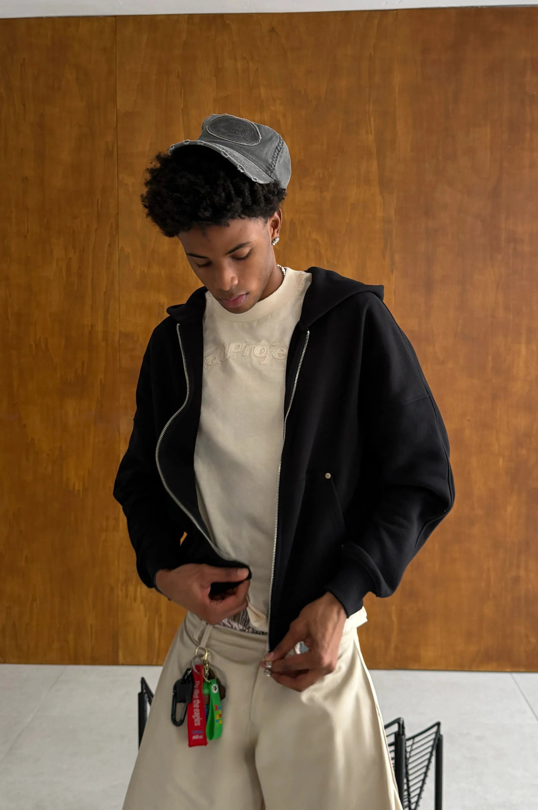 Black zip-up hoodie with hood and cream graphic on the back
