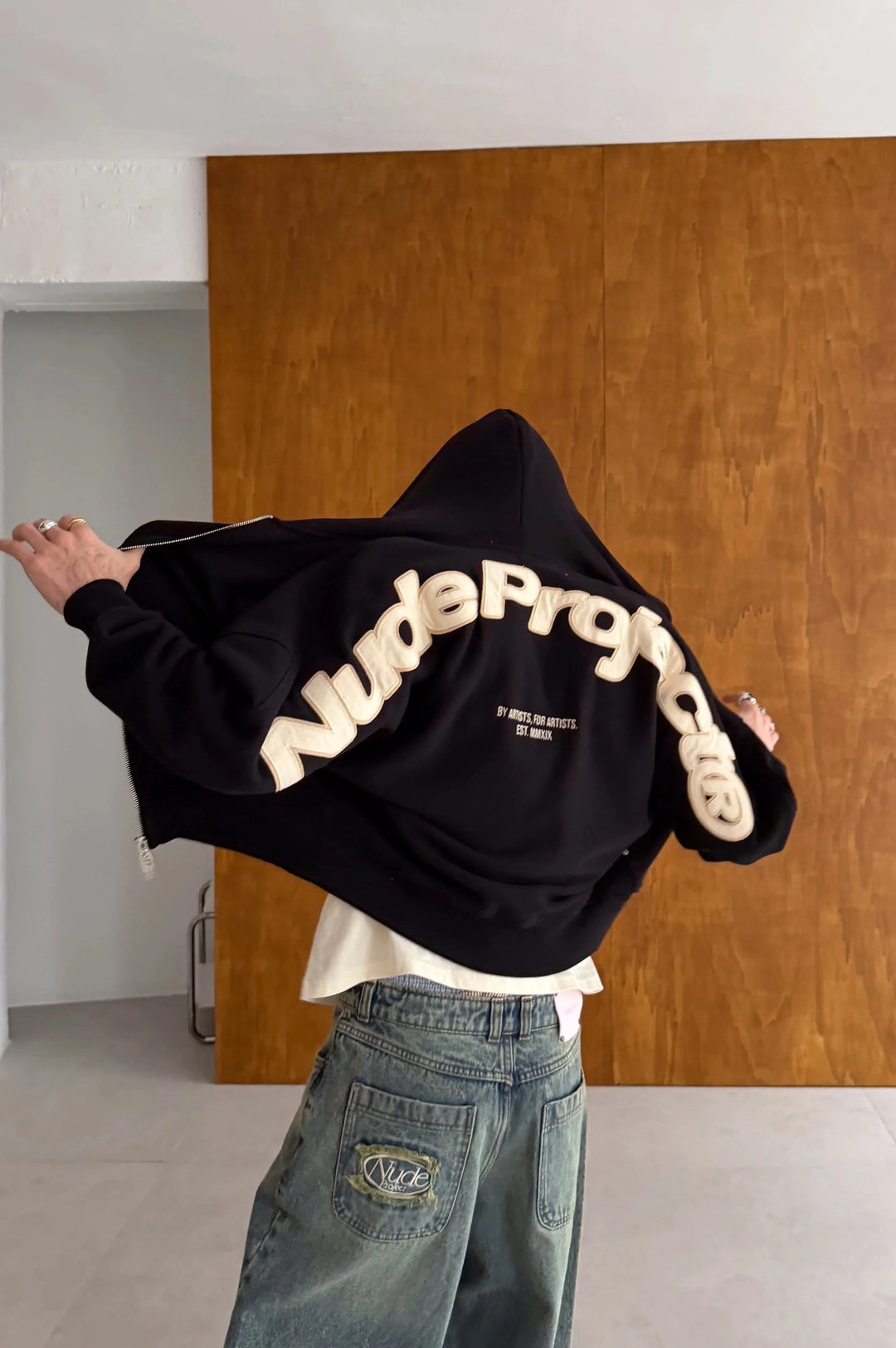 Black zip-up hoodie with hood and cream graphic on the back