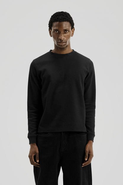 Men's black long-sleeve crew-neck top with textured finish and ribbed cuffs