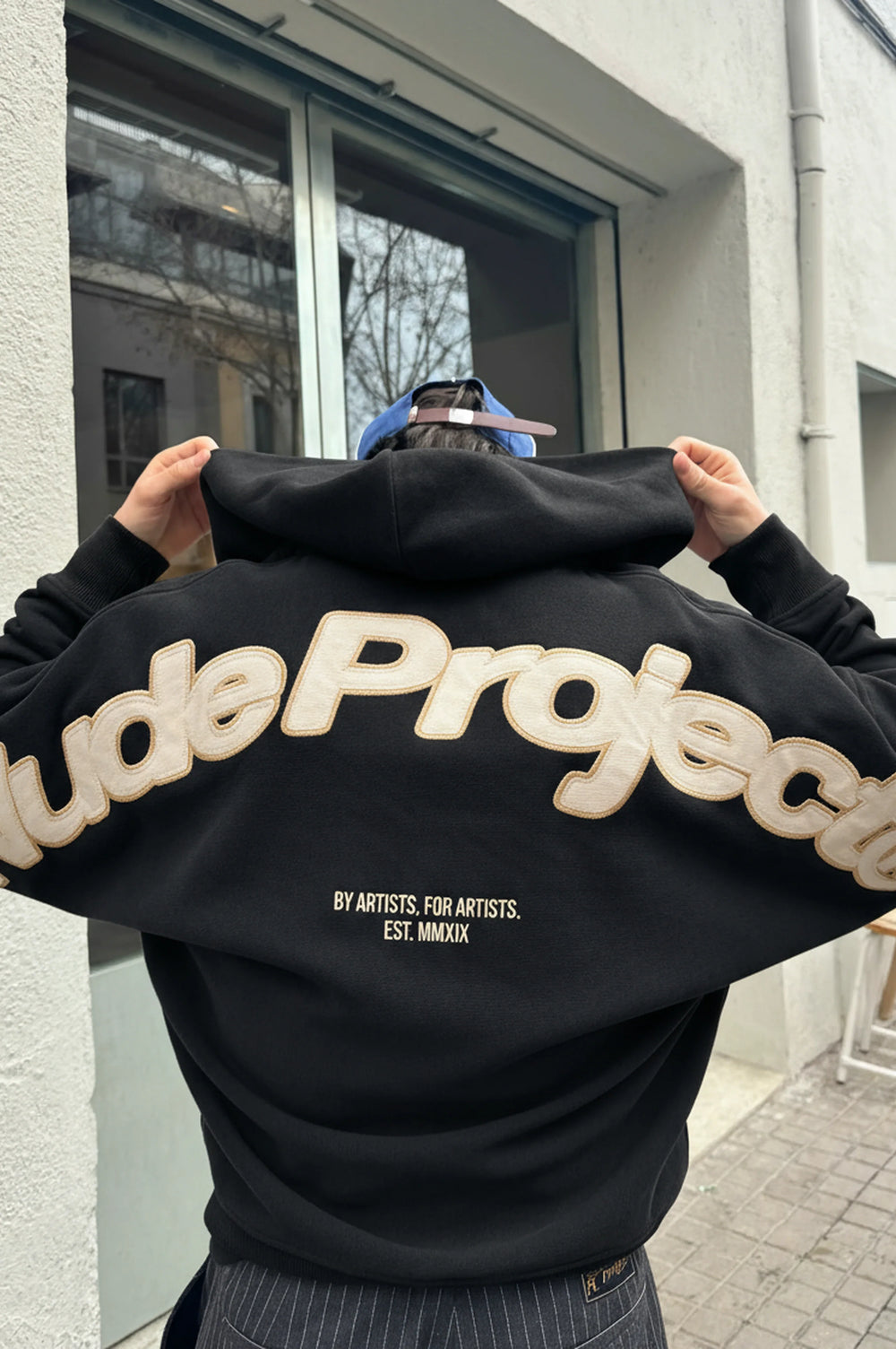 Black zip-up hoodie with hood and cream graphic on the back