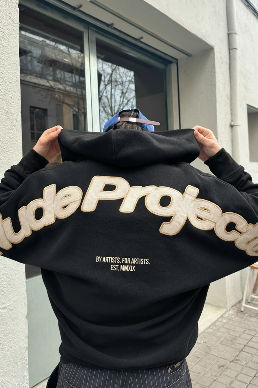 Black zip-up hoodie with hood and cream graphic on the back