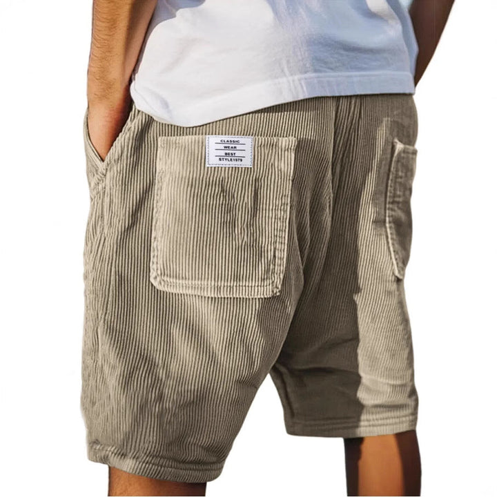 Men's grey ribbed shorts with stitched back pockets, shown from the rear on a model wearing a white t-shirt
