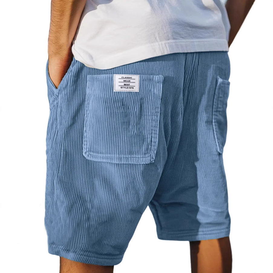 Men's grey ribbed shorts with stitched back pockets, shown from the rear on a model wearing a white t-shirt