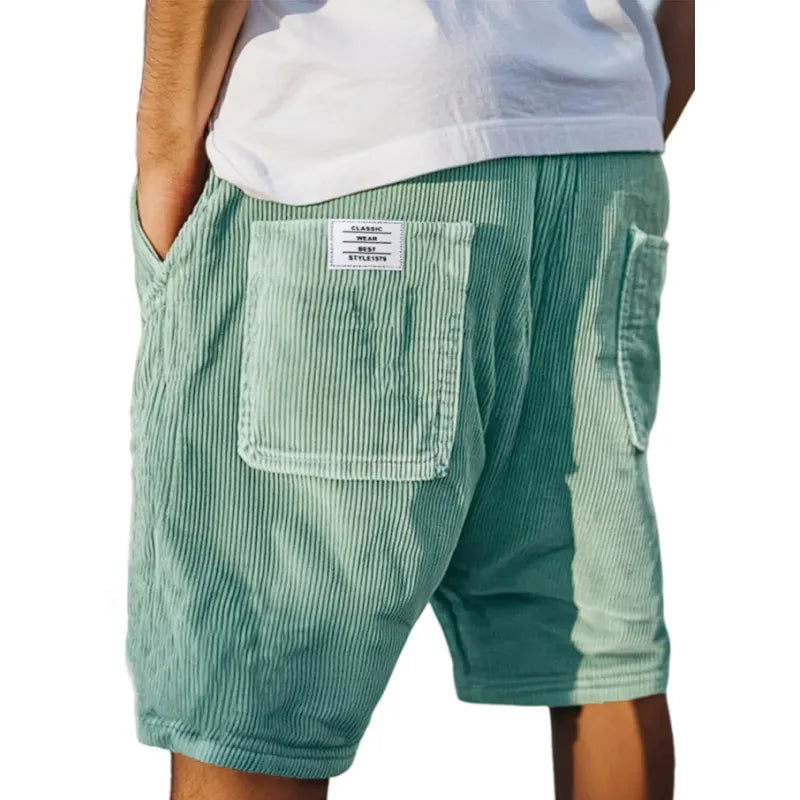 Men's grey ribbed shorts with stitched back pockets, shown from the rear on a model wearing a white t-shirt