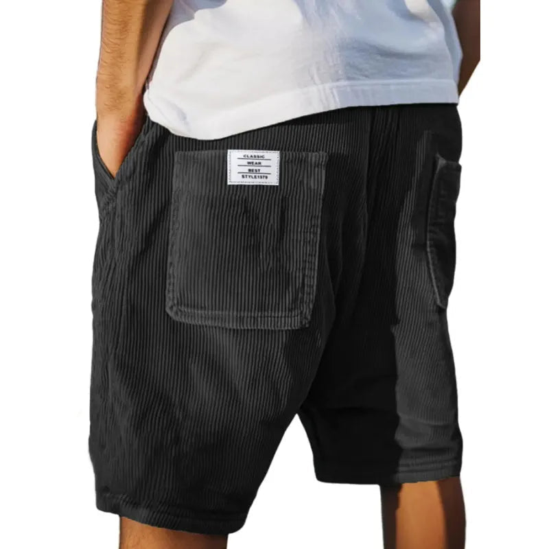 Men's grey ribbed shorts with stitched back pockets, shown from the rear on a model wearing a white t-shirt