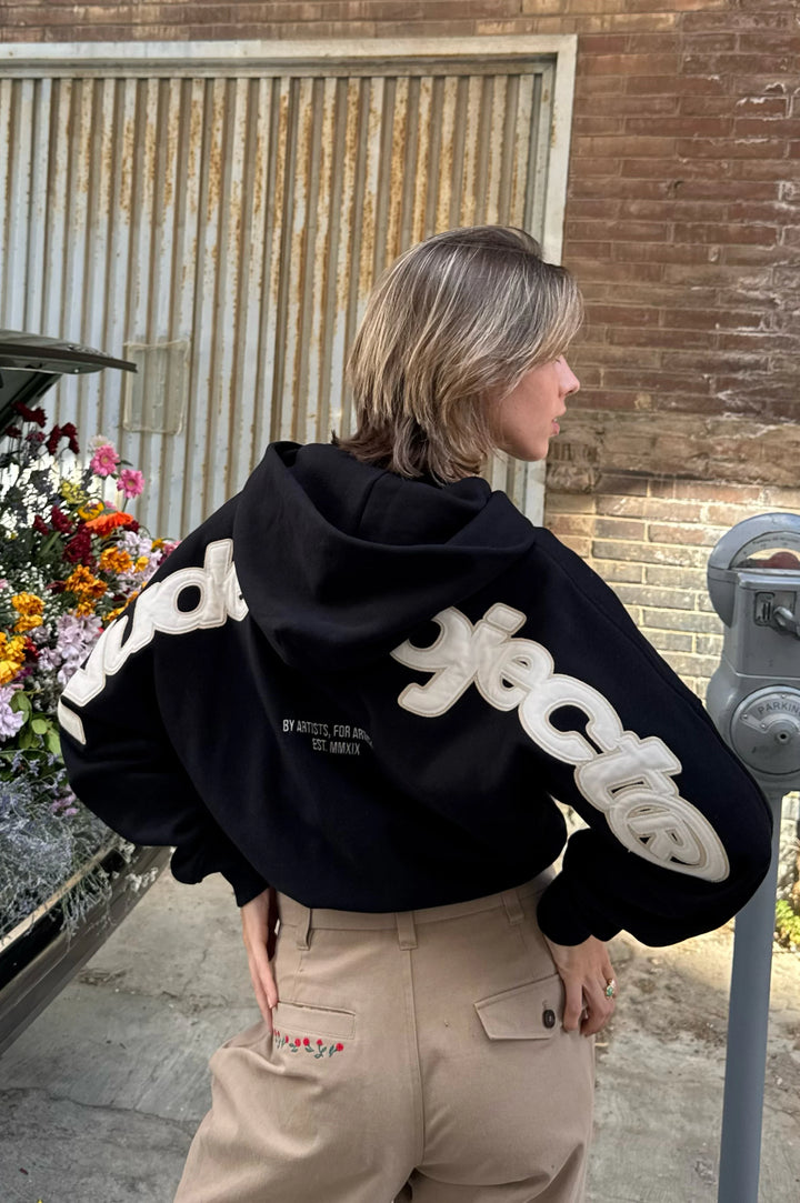 Black zip-up hoodie with hood and cream graphic on the back