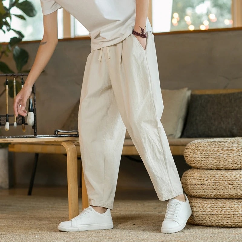 Men's tapered ankle pants with drawstring waist in cream, displayed with white sneakers